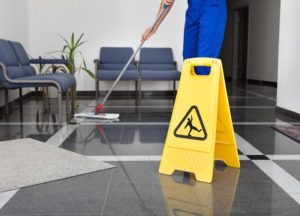 Cleaning person and a slippery when wet sign