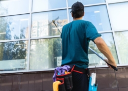 An employee of a professional window cleaning service washes the exterior windows with special devices