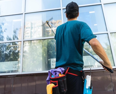 An employee of a professional window cleaning service washes the exterior windows with special devices