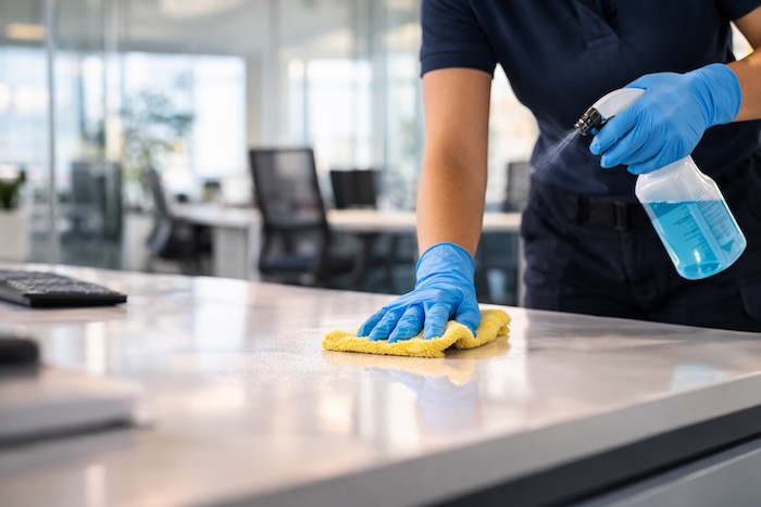 Professional commercial cleaner disinfecting office desk in modern workspace
