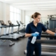 Professional cleaner disinfecting gym equipment in a Kitchener Waterloo fitness centre